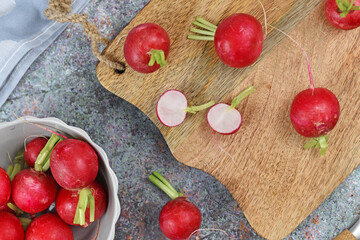 Raw cultivated radish cut in half on cutting board surrounded by whole vegetables