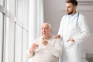 Doctor giving medicine to senior man in clinic. Prostate cancer awareness concept