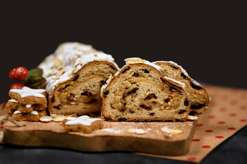Slices of German Stollen cake, a fruit bread with nuts, spices, and dried or candied fruits, coated with powdered sugar traditionally served during Christmas time on dark background