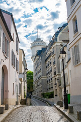 Paris, romantic street in Montmartre, typical buildings and the water tower