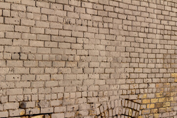 Full frame abstract texture background of an old shabby chic beige painted exterior brick wall with significant aging and mortar erosion
