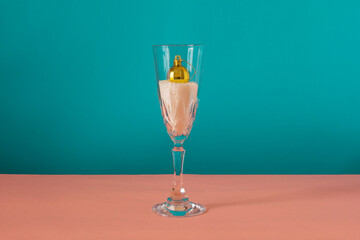 Yellow ornament inside the glass on pink and blue background. Winter concept