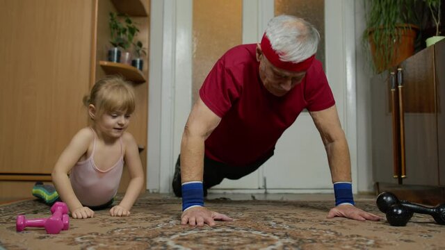 Child Kid Girl And Senior Grandfather In Sportswear Making Sports Workout At Home. Active Old Mature Man With Granddaughter Doing Fitness Push-up Exercises. Healthy Lifestyle. 6k Downscale Slow Motion