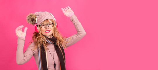 adult or senior woman dancing with headphones and winter clothes