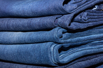 Closeup shot of stack of folded blue jeans in fashion store. Shopping and clothing industry concepts