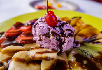 Ice cream, fruit, and chocolate syrup on top of a waffle