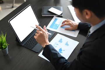 Fototapeta premium Businessman using computer tablet researching process accounting and analysis market graph data stock information review on the table in office.