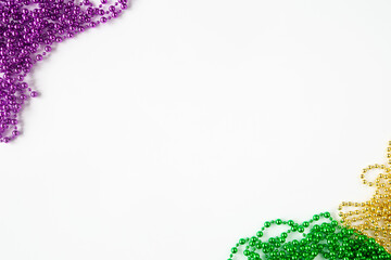 Mardi gras background, border on white with purple gold green beads and copy space - obrazy, fototapety, plakaty