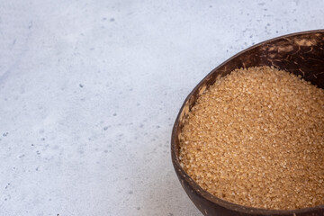 brown sugar in a coconut bowl. sugar against an out of focus wood background - copy space