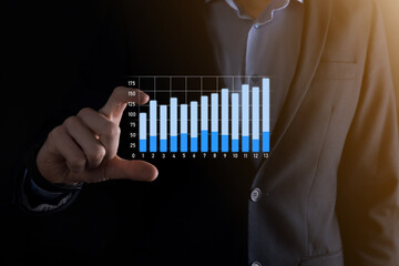 Business man holding holographic graphs and stock market statistics gain profits. Concept of growth planning and business strategy. Display of good economy form digital screen.