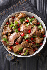 Kuchmachi Georgian dish made from offal with spices, onion and pomegranate close-up in a bowl on the table. Vertical top view from above