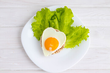 breakfast scrambled eggs in the form of a heart on bread and salad.concept of Valentine's day.on a white background