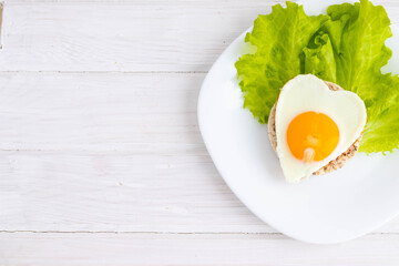 breakfast scrambled eggs in the form of a heart on bread and salad.concept of Valentine's day.on a white background