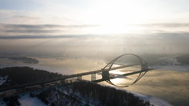 winter sunny panorama of the city on the background of the sunset. Novosibirsk bridge and winter river with ice floes