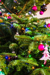 A vertical shot of a beautiful Christmas fir tree decorated with ornaments, balls and led lights