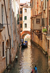 Obraz na płótnie Canvas Venetian street with gondola on the narrow channel, Italy.