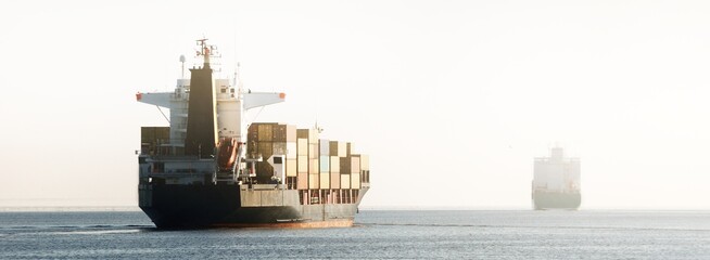 Large cargo container ship leaving the port, sailing in a still sea water. Panoramic view. Freight transportation, nautical vessel, global communications, industry, carrying, logistics, commerce © Alex Stemmer