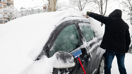 Cleaning snow off car in winter season.