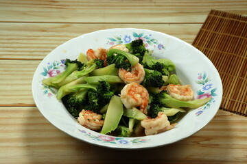 Fried and stirred cutting fresh broccoli with peeled shrimp serving on the plate. Famous seafood menu in Asia restaurant. 