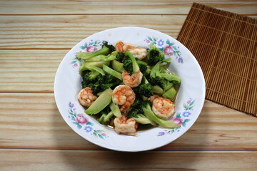 Fried and stirred cutting fresh broccoli with peeled shrimp serving on the plate. Famous seafood menu in Asia restaurant. 