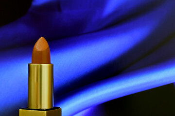 Close-up red brown lipstick  on blue shiny cloth background .