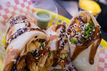 Burritos covered with sauce and seeds on a plastic basket