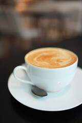 Coffee to go. Fresh latte in a cup on a black wooden table in a cafe.
