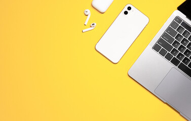 Colorful flat lay shot of a silver grey laptop computer, white smartphone, earphones with a...