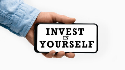Closeup of a male hand holding Smartphone with text INVEST IN YOURSELF on display