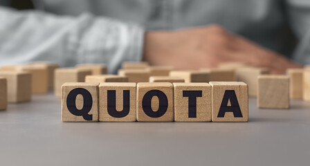 The word QUOTA made from wooden cubes. Shallow depth of field on the cubes - obrazy, fototapety, plakaty