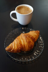 Breakfast with coffee and croissants. High angle view, black background.