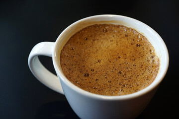 Coffee to go. Fresh latte in a cup on a black wooden table in a cafe.