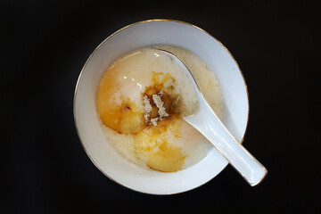 Malaysia and Singapore traditional breakfast half-boiled eggs in a bowl with soy sauce and white pepper.