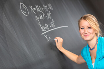 Pretty young college student or teacher washing the chalkboard/blackboa rd during class (shallow DOF; color toned image)