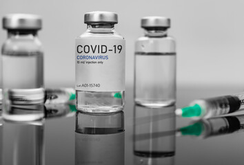 Covid19 Vaccine syringes and medicine bottles in reflecting dark table