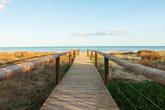 Beautiful wooden boardwalk leading to the beach. Perfect landscape photography with a dreamlike seascape horizon. POV postcard shot.
