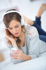 Naklejka premium woman wearing headphones looking at smartphone with shocked expression