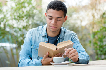 handsome young man drinking coffee while reading book
