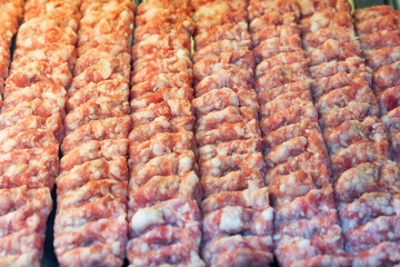 Cooking raw pork kofta marinated in spices on a skewer