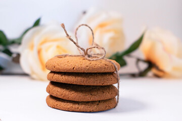 A stack of oatmeal cookies, blurred flowers in the background. Gifts for loved ones. The photo