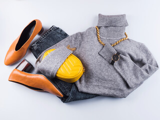 Fashion outfit with gray woolen turtle neck and illuminated yellow handbag clutch, golden accessories. Lady winter autumn style in trendy colors.