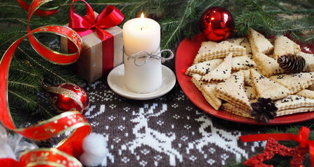 Christmas background with homemade shortbread cookies and red Christmas decor on a knitted knitted background with deer. Congratulatory background.