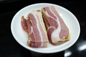 Slices of raw fresh pork belly cut on a white plate