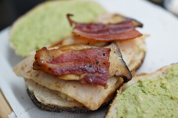 Toasted bread with grilled bacon, mushroom and avocado spread close up.