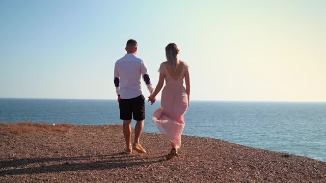 A young couple walks along the seashore at a romantic meeting. Honeymoon. Valentine's Day.