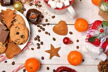 sweet food top view background for merry christmas or new year holiday decoration - chocolate candies, tangerines, cookies, marshmallow and cocoa latte on white wood