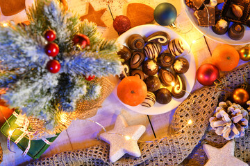 sweet food top view background for merry christmas or new year holiday decoration with night illumination - chocolate candies, tangerines, cookies on white wood