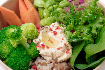 Healthy vegan lunch bowl. Avocado, quinoa, tomato, cucumber, 
carrot, hummus, green peas and radish vegetables salad. 