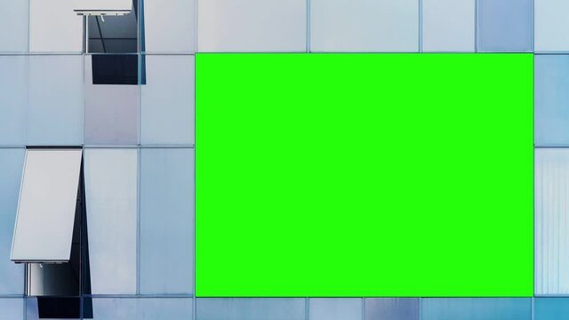 Large chromakey advertising billboard with mockup on glass wall of modern office building