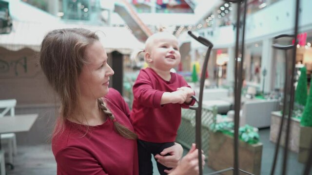 Mom and daughter in their arms swing a flower stand in a shopping center.